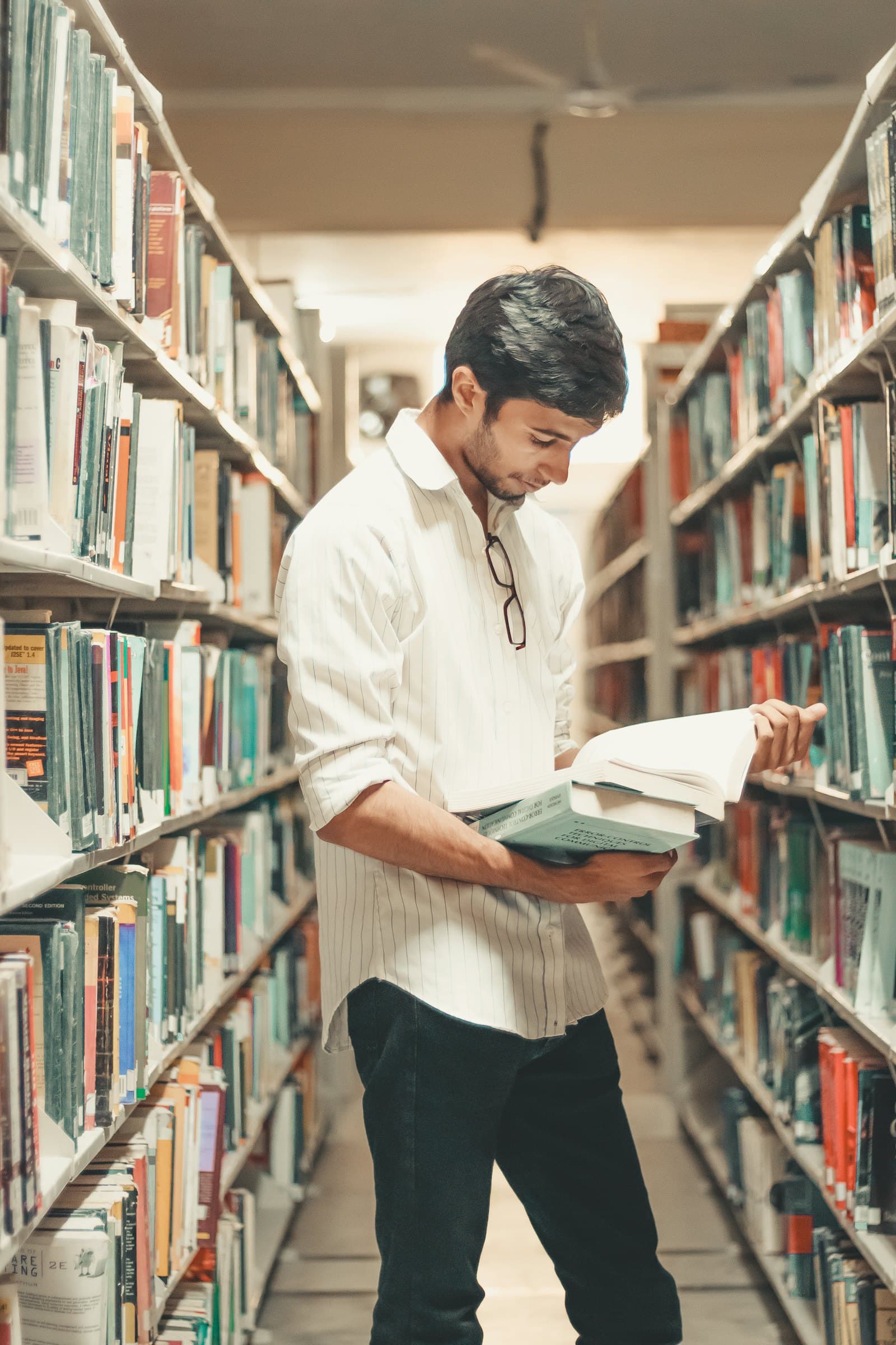 Étudiant lisant un ouvrage dans une bibliothèque